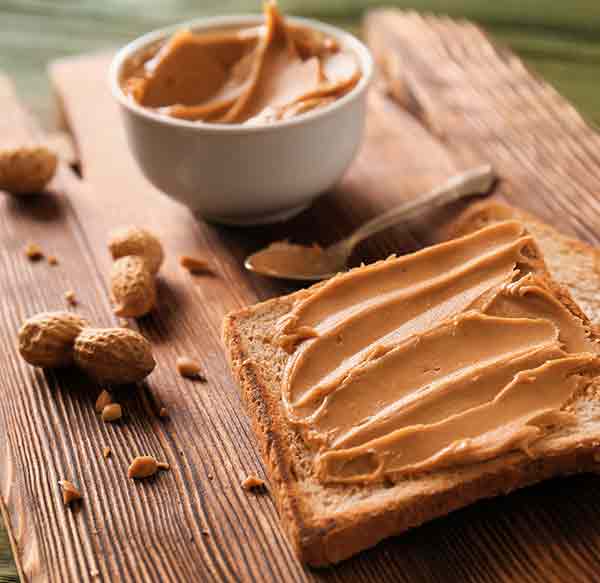 bread spread with peanut butter on a wooden chopping board