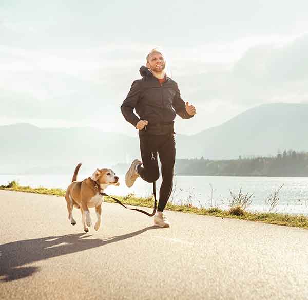 man running along the waterfront with beagle